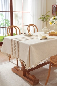 Close-up detail of geometric embroidery and handmade tassels on linen table runner