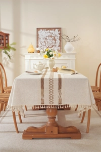 Detail of linen table runner with brown geometric wave pattern and fringed tassels