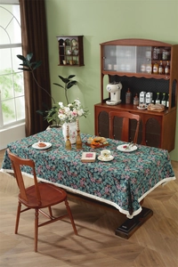 Detailed texture of dark green floral tablecloth with ivory lace fringe and retro pattern