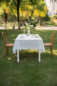 Detail of French cotton tablecloth with colorful geometric patterns and white pom-pom fringe