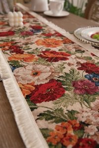 Close-up of vintage floral jacquard table runner with thick white fringe tassels