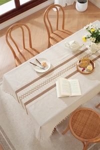 Detail of beige linen table runner with brown geometric pattern and delicate tassels