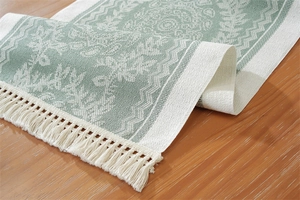 Close-up of woven table runner with teal mandala jacquard and cream fringe tassels