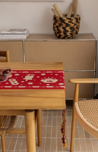 Close-up of festive red table runner featuring jacquard floral patterns and colorful tassels