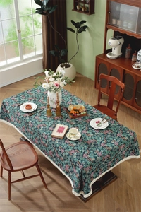 Detail of vintage floral tablecloth with dark green background and elegant fringe edges