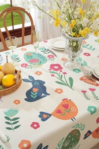 Detail of Easter tablecloth with printed rabbits and flowers and fringed edges on table