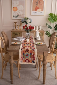 Detail of bohemian geometric woven table runner with white decorative tassels on wood