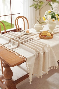 Detail view of linen table runner featuring brown geometric patterns and white fringe tassels