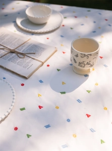 Close-up of French cotton tablecloth with colorful geometric embroidery and ruffled edges