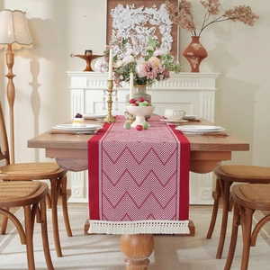 Detail of red jacquard table runner with white zigzag pattern and woven tassels