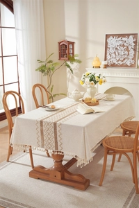 Detailed close-up of beige linen table runner with geometric weaving and fringe trim
