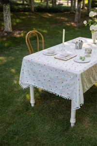 Close-up of colorful geometric pattern and white pom-pom trim on French cotton tablecloth