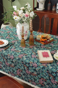 Detailed close-up of dark blue jacquard floral tablecloth with white fringe tassels
