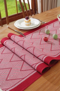 Close-up of red and white jacquard table runner with geometric diamond patterns on wood