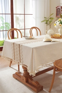 Close-up of minimalist linen table runner with geometric embroidery and cotton tassels