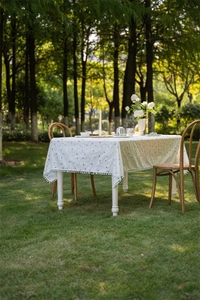 Macro detail of French cotton tablecloth featuring colorful geometric embroidery and tassels