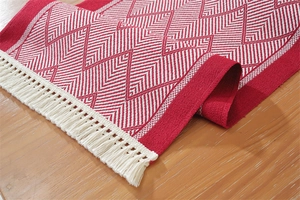 Detailed view of red and white chevron jacquard table runner with thick white tassels