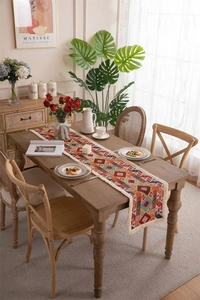 Detail of bohemian geometric jacquard table runner with white fringe on wooden table