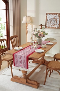 Detailed view of red Christmas table runner with reindeer motifs and white fringe