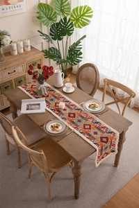 Close-up of ethnic geometric pattern table runner with tassels on a wooden table