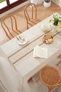 Close-up of beige linen table runner with woven geometric patterns and fringe edges