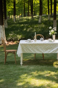 Detail of cotton tablecloth with colorful geometric patterns and white pom pom fringe