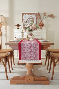 Detailed close-up of red and white reindeer Christmas table runner with white tassels