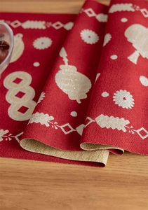 Detailed macro view of red jacquard table runner with golden lantern and floral patterns
