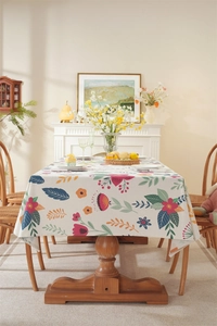 Detail of floral Easter tablecloth with tassels on a rustic wooden dining table