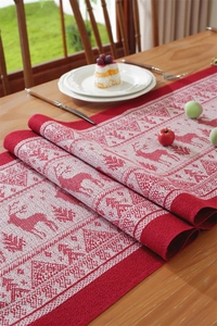 Detail of Christmas table runner with reindeer and pine tree jacquard patterns on wooden table
