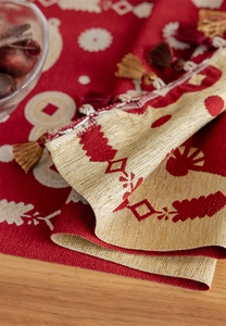 Detail of red and gold jacquard table runner with traditional coin patterns and tassels