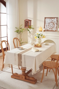 Detailed close-up of beige linen table runner with brown hollow lace and elegant tassels