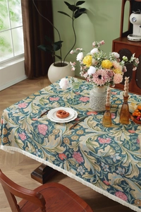 Close-up of vintage floral jacquard tablecloth with intricate leaf patterns and white tassels