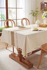 Detail of linen table runner featuring beige crochet lace and decorative tassels