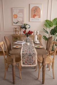 Close-up of vintage floral jacquard table runner with delicate cream tassels on wood