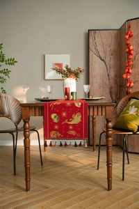 Detail of red festive table runner with golden fish patterns and multicolored tassels