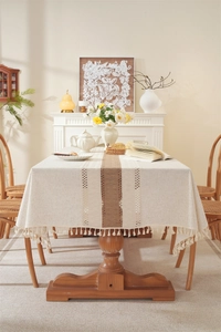 Detail of linen table runner with coffee-colored patchwork, lace, and tassel trim