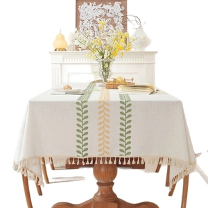 Rectangular cream linen tablecloth with embroidered green leaves and tassels