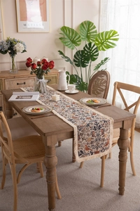 Detail of vintage bird floral table runner with handmade tassels on wooden desk