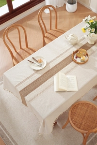 Detail of linen table runner with hollow woven pattern and fringe tassel decoration