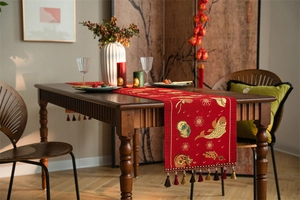 Detail view of red jacquard table runner with golden koi fish embroidery and silk tassels