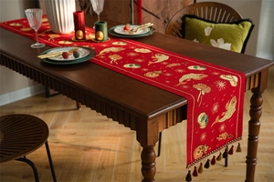 Detail of red festive table runner with golden embroidery, jacquard texture, and tassels