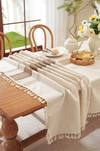 Close-up of linen table runner with hollow lace, brown stripes and beige fringe tassels