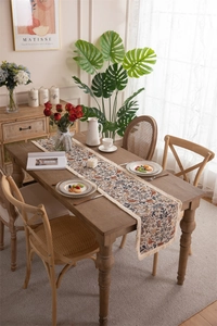 Detail of vintage floral birds jacquard table runner with decorative beige fringe tassels