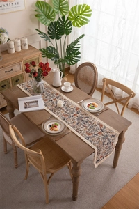 Detailed view of vintage table runner featuring floral bird patterns and beige tassels