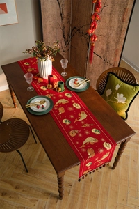 Detail of red festive table runner with golden brocade koi and tassel ornaments