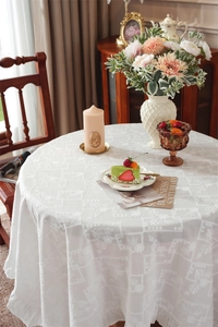 Close-up of white cotton tablecloth showing floral embroidery and ruffled edge details