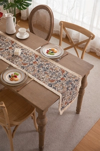 Detail of vintage table runner with floral bird prints and delicate white tassels