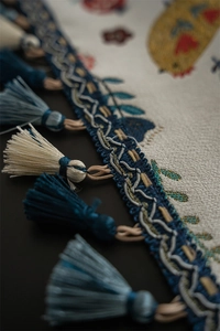 Close-up of Easter table runner tassels and woven fabric with chick and flower patterns
