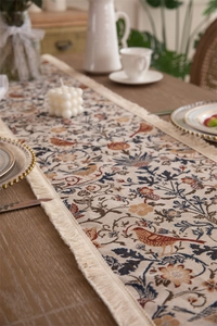 Detail of vintage jacquard table runner with bird and flower patterns and fringe